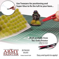 Advertisement for The Army Painter Jungle Tuft with tools and text on a grid background