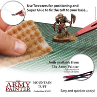 Advertisement for The Army Painter mountain tuft with tools and text on a grid background